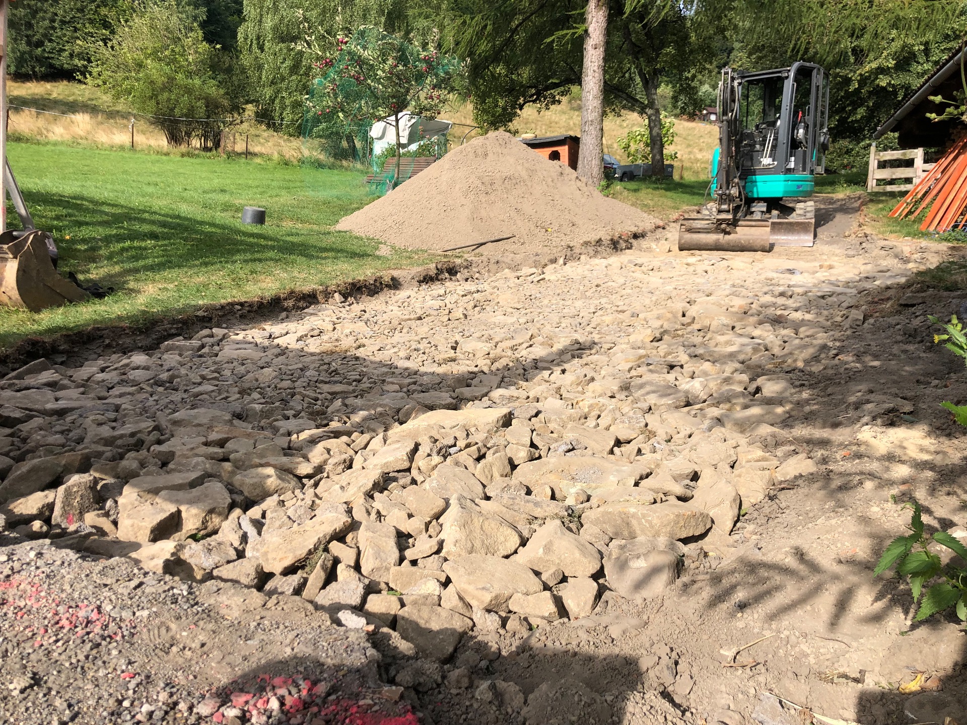 2 oddělené frakce - kameny jako základ pod příjezdovou cestu a hlína pro terénní úpravy.